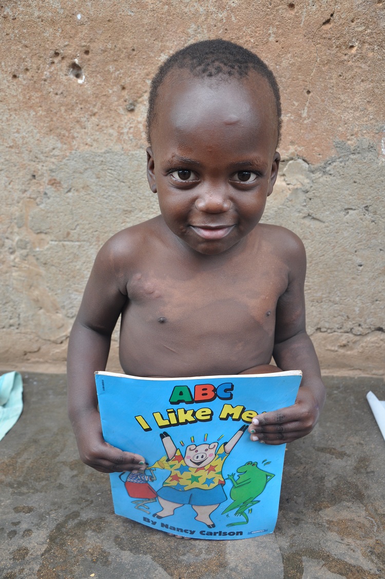 Nicholas reading books after a bucket bath in Uganda