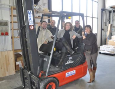 Perched atop a forklift in Genoa, surrounded by our Italian distribution team in their warehouse.